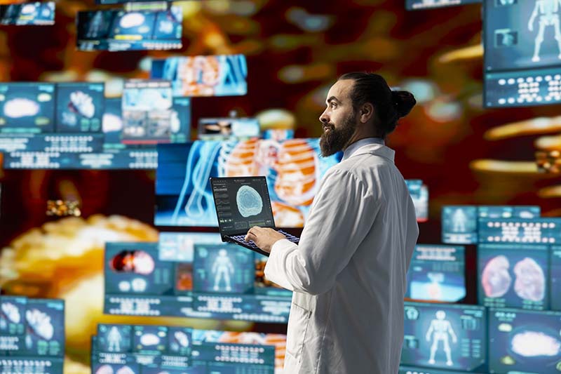 man surrounded by computers screens showing images of medical ai