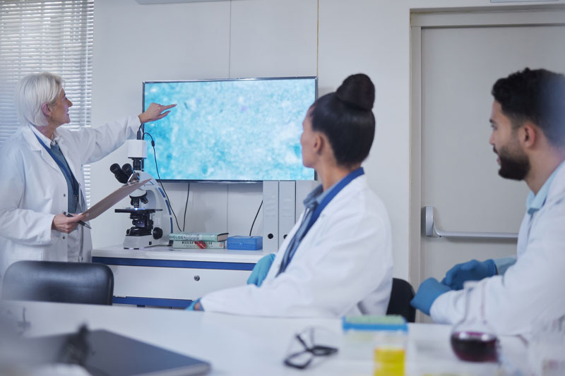 two women and one man viewing a computer screen in a lab