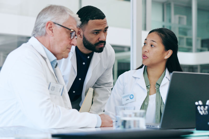 group of doctors conferring around a laptop