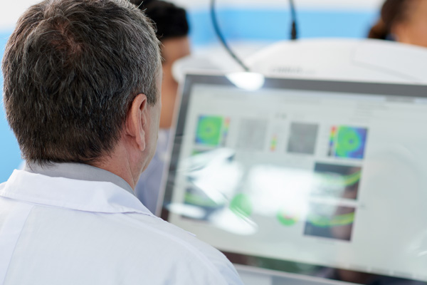 view of computer screen from behind a male doctor