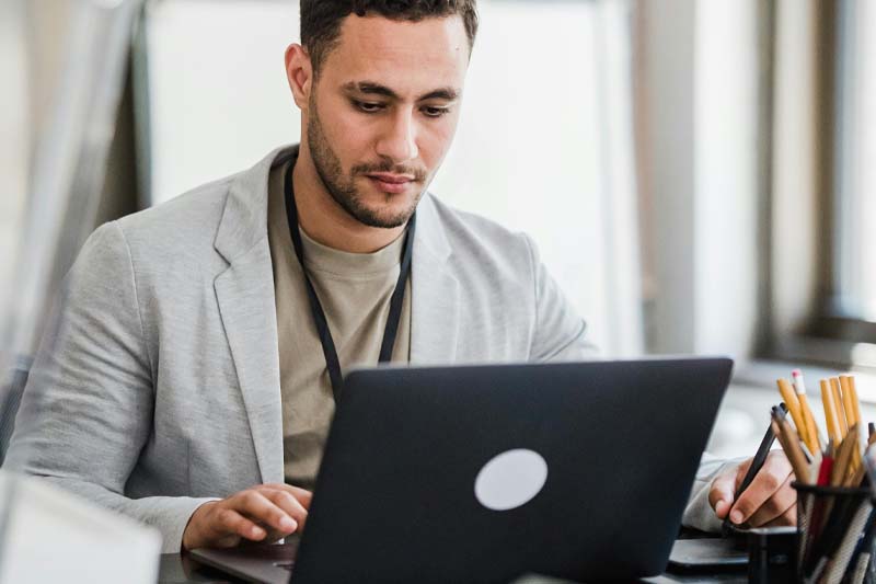 Man in a gray sport jacket working at at laptop
